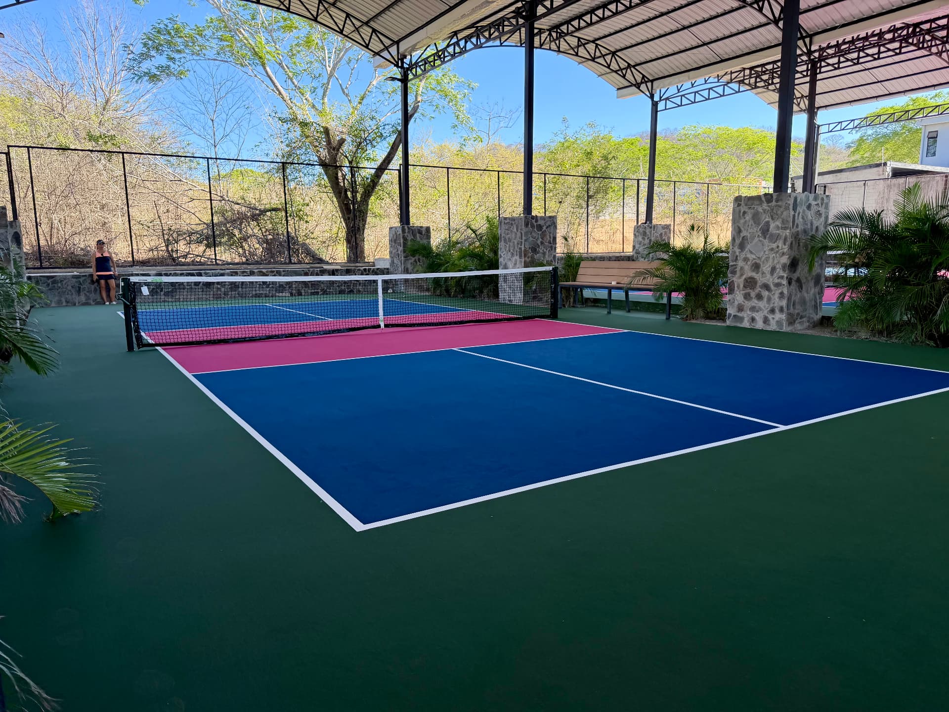 Covered pickleball courts framed by stone columns and palms