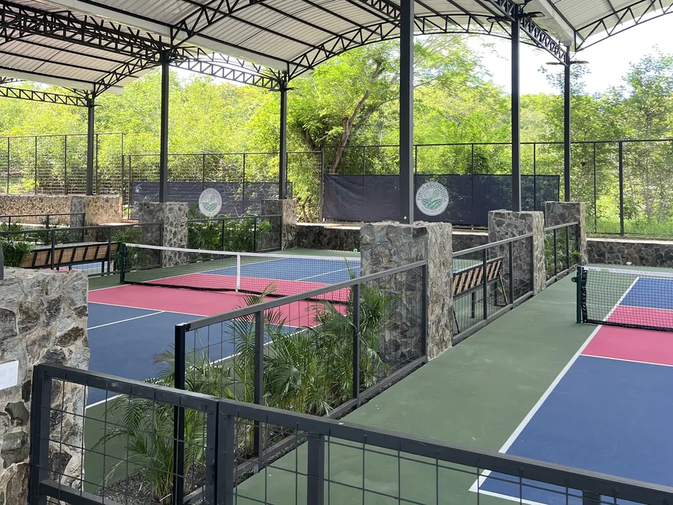 Walkway between covered pickleball courts, with stone pillars and planters